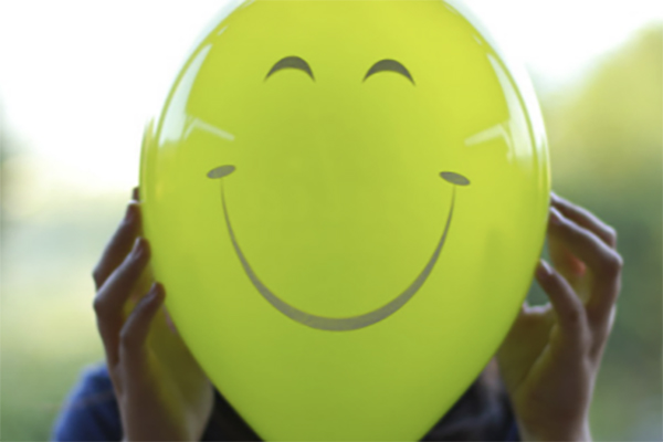 person with a ballon in front on their face happy face on balloon